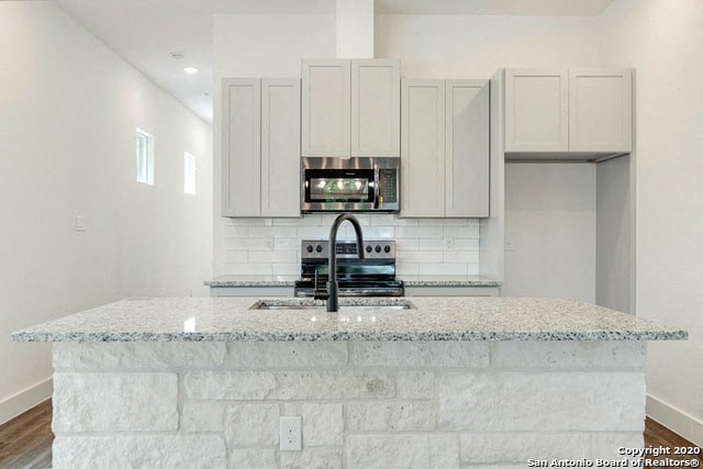 a kitchen with white cabinets and a marble counter top