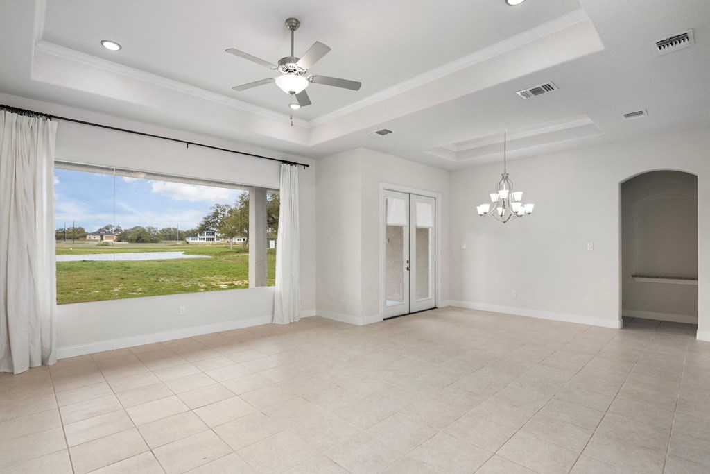 an empty living room with a large window and a ceiling fan