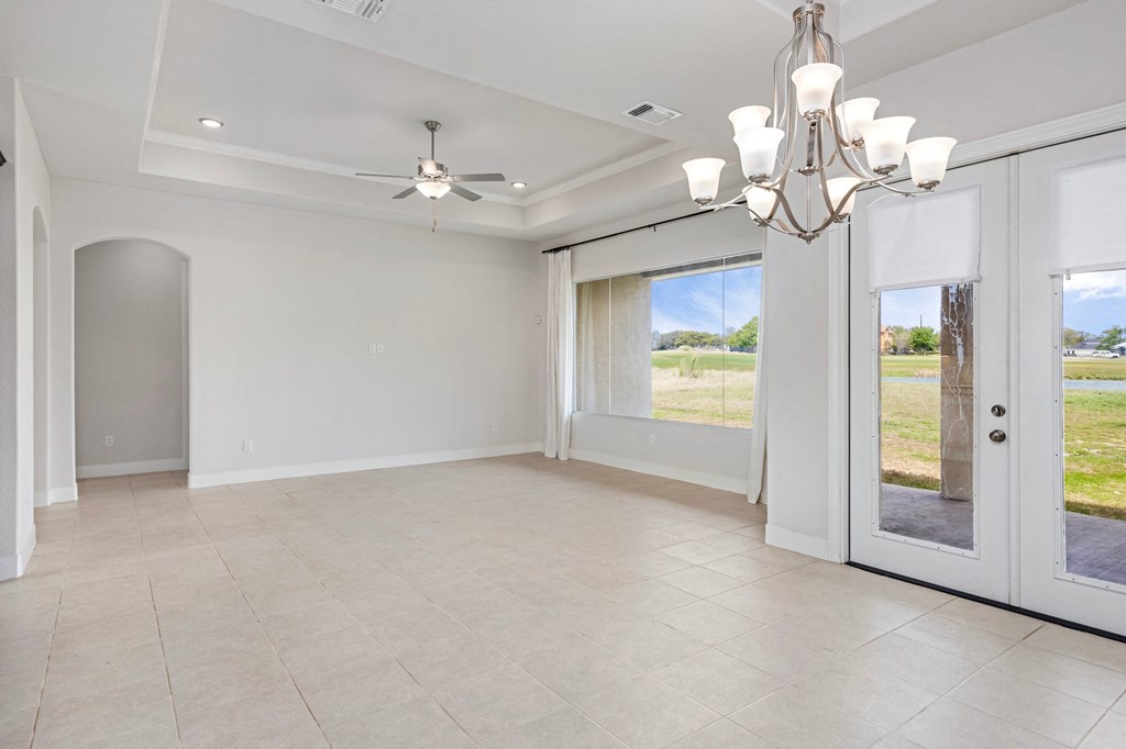 an empty living room with large windows and a ceiling fan