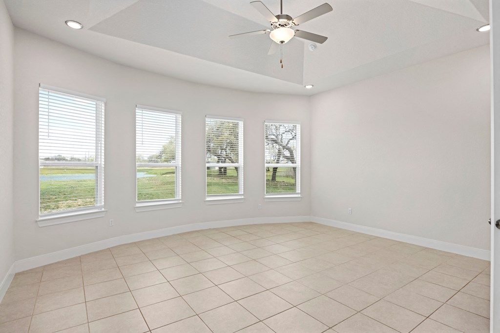 an empty living room with windows and a ceiling fan