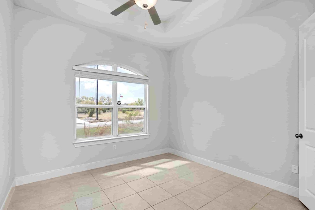 an empty living room with a window and tiled floors