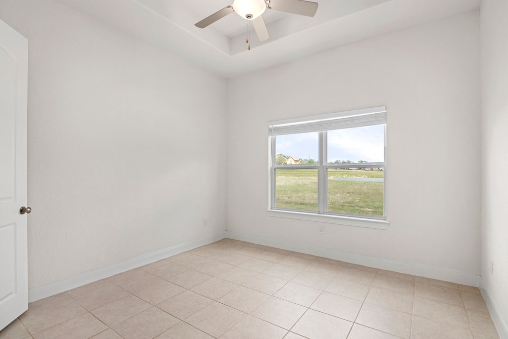 an empty living room with a window and a tiled floor