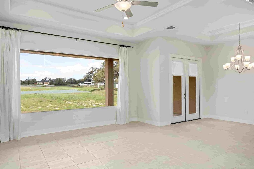 an empty living room with a window and a ceiling fan