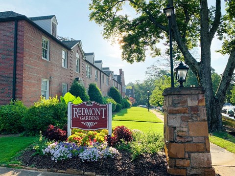 a sign for redmond gardens in front of a brick building