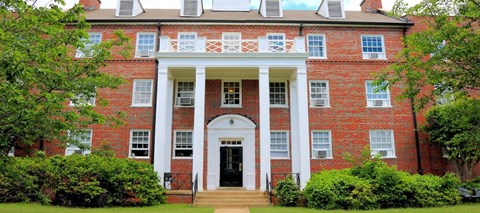 a red brick building with white columns and a black door