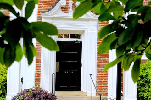 the front door of a brick building with a black door
