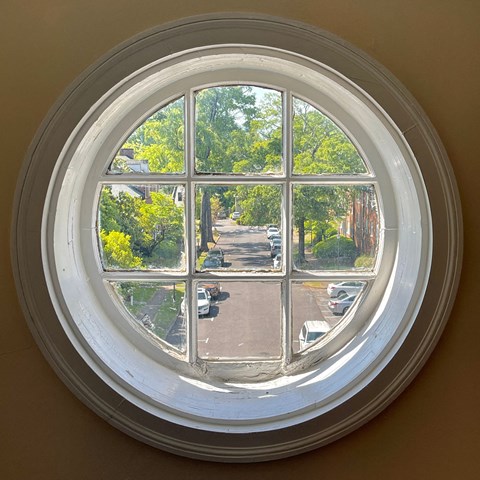 a round window with a view of a street and trees