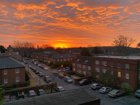 a sunset over a city street with cars and buildings