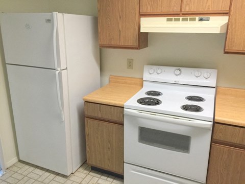 A white refrigerator stands next to a white stove in a kitchen.