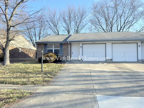 a house with two white garage doors and a driveway