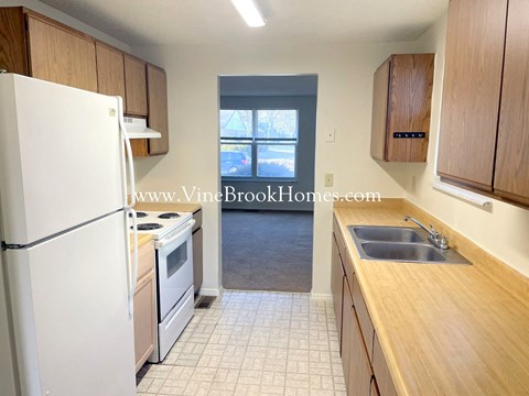 a small kitchen with wooden cabinets and white appliances and a white refrigerator