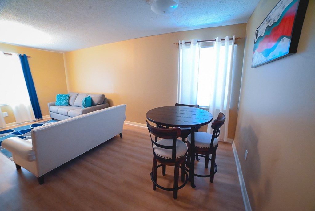 a living room and dining room with a table and chairs