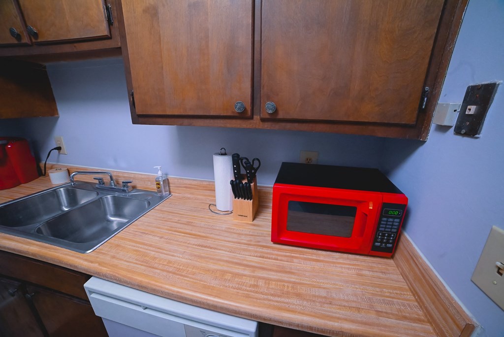 a red microwave on a kitchen counter next to a sink