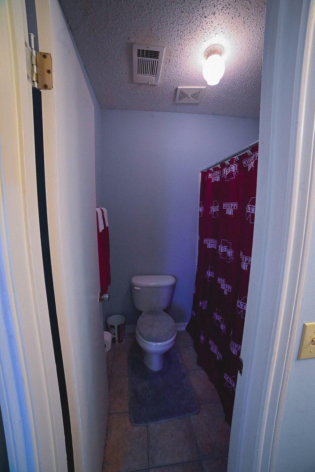 a small bathroom with a toilet and a red shower curtain