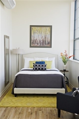 A bedroom with a bed, a chair, and a painting on the wall.