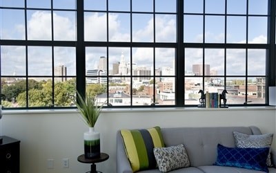 A living room with a grey couch and a green pillow.