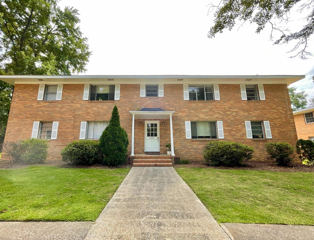 a brick house with a sidewalk in front of it