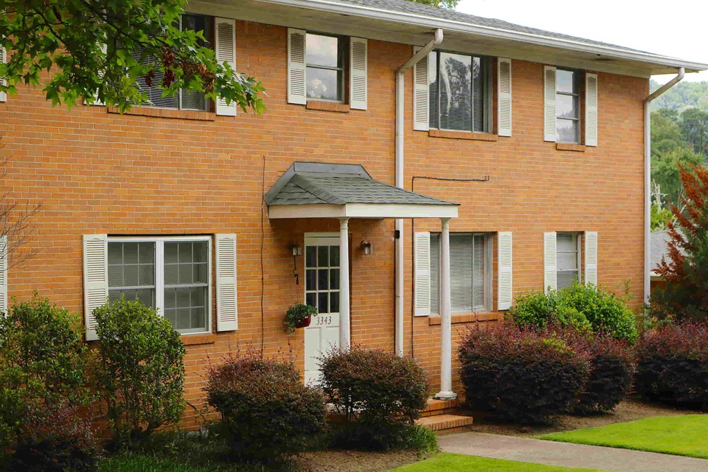 a red brick house with a white door and a sidewalk