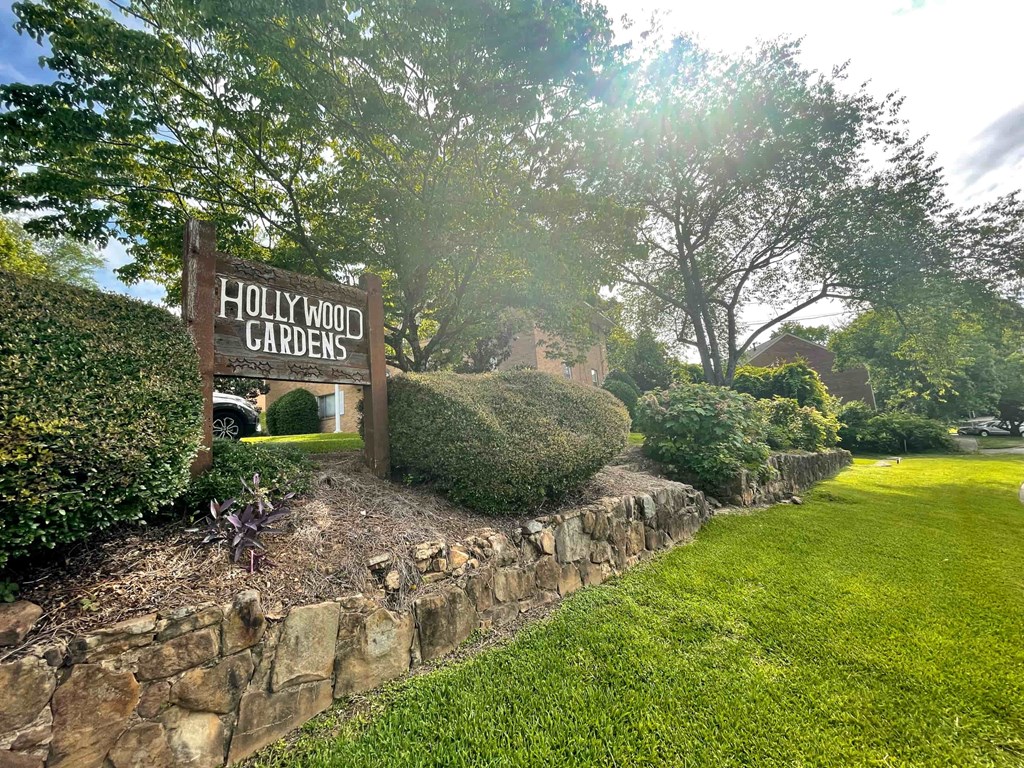 a sign for hollywood gardens in front of a stone wall