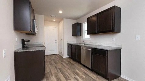 a kitchen with black cabinets and a wood floor