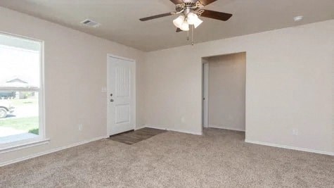 an empty living room with a ceiling fan and a door