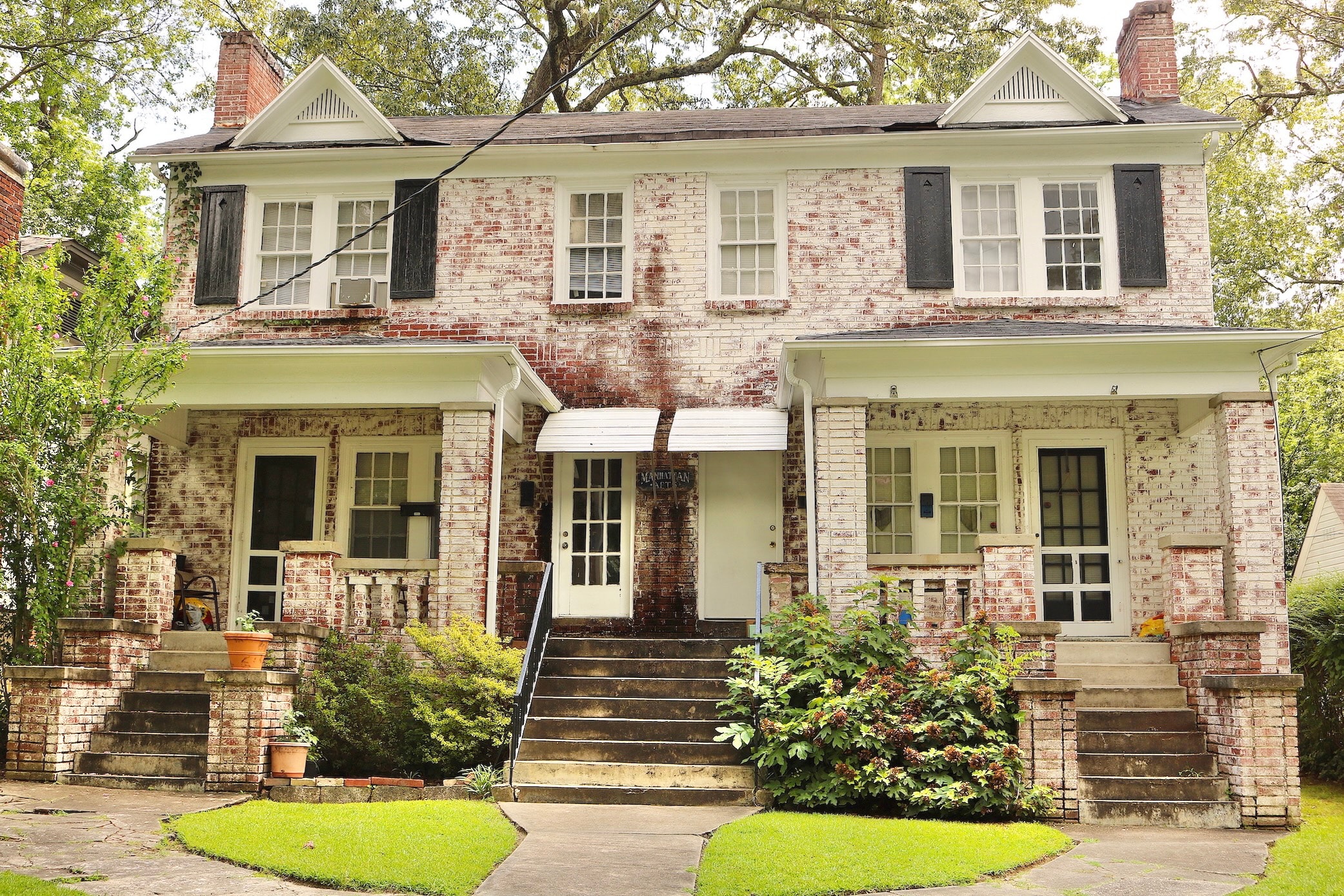 an old brick house with black shutters and a lawn