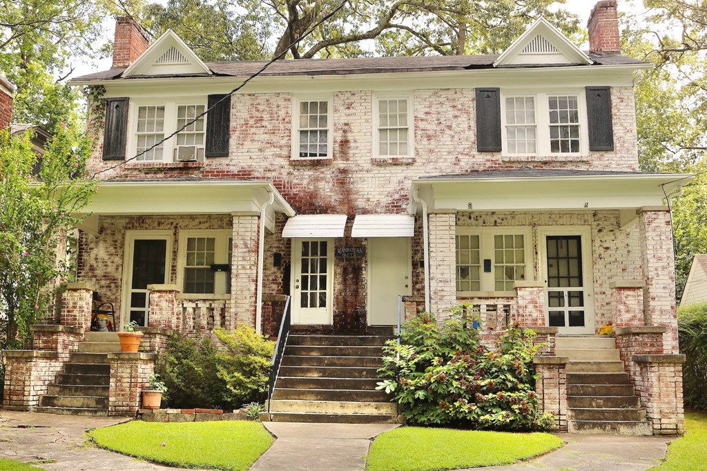 an old brick house with black shutters and a lawn