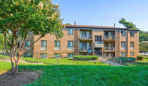 a brick apartment building with a yard and a tree