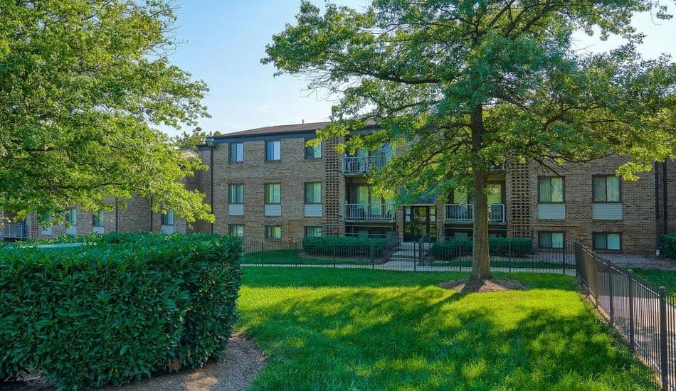 a large brick apartment building with a grass yard and trees