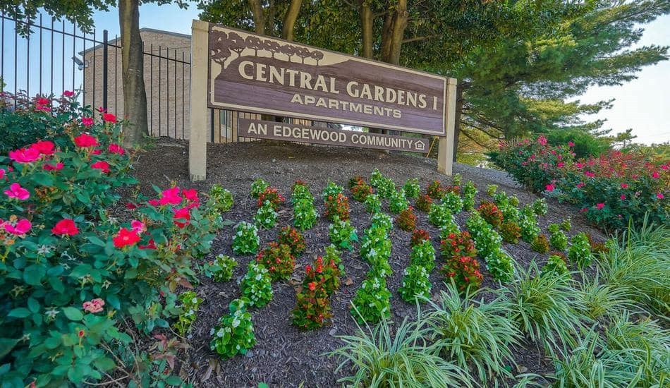 a sign for central gardens apartments in front of flowers