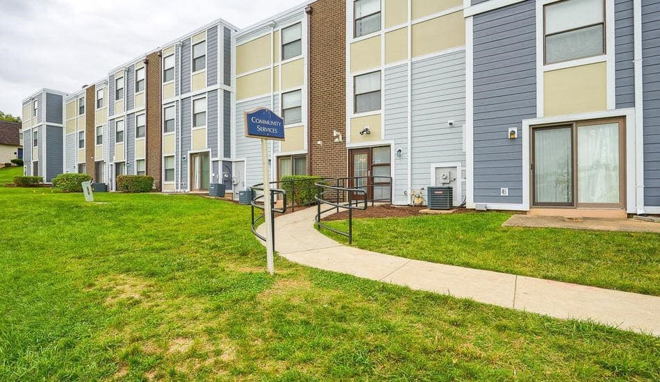 an apartment building with a sidewalk and green grass
