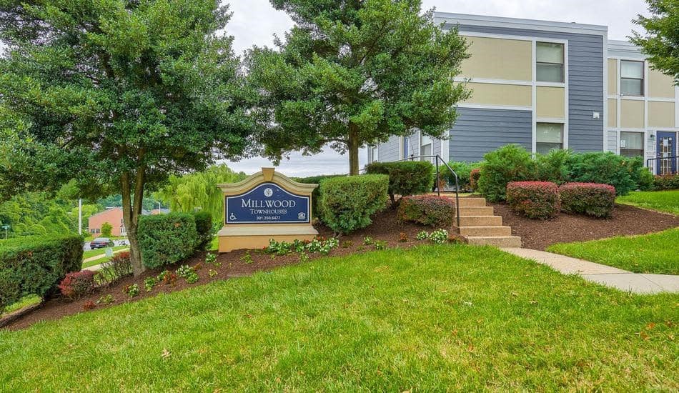 a building with a sign in front of a lawn and trees