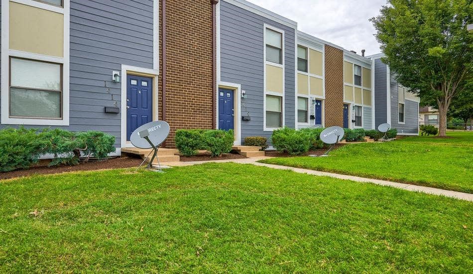 an apartment building with three satellite dishes in the grass