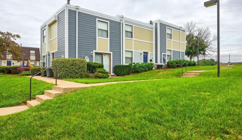 a blue and yellow apartment building with stairs and grass