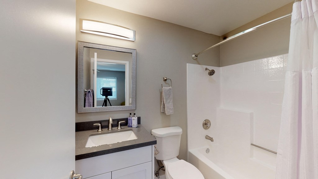 a bathroom with a toilet sink and shower and a mirror