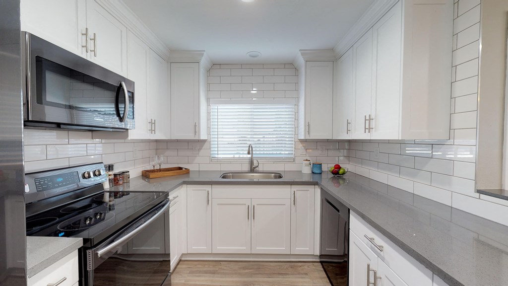 a renovated kitchen with white cabinets and stainless steel appliances