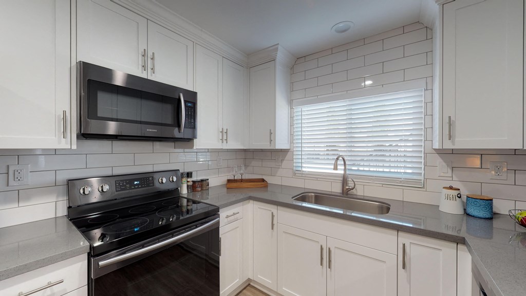 a kitchen with white cabinets and black appliances