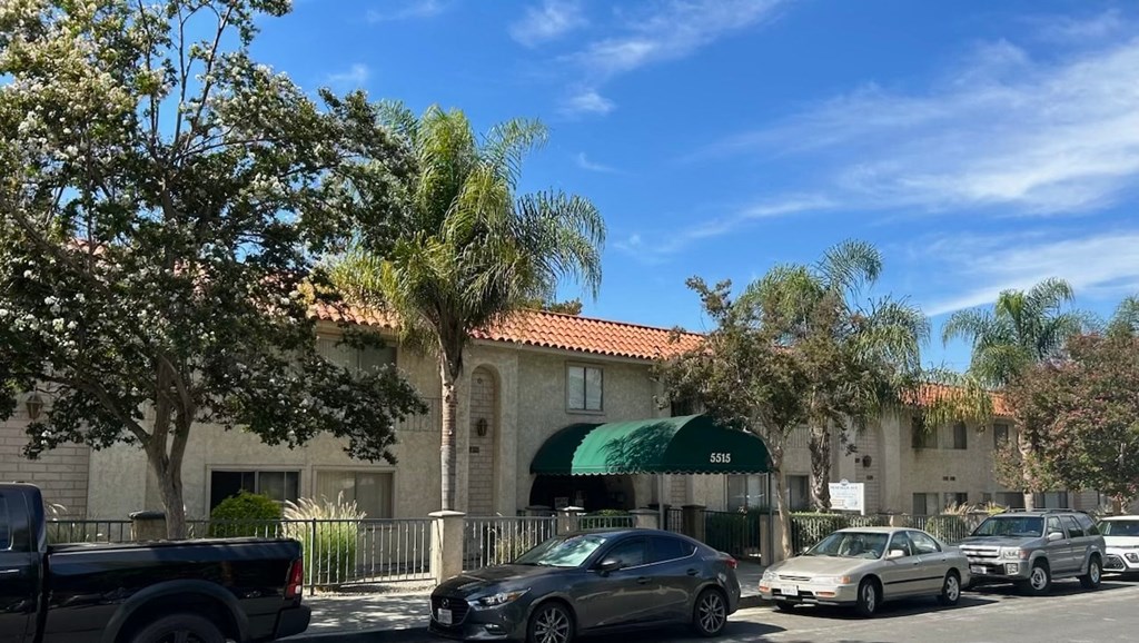 a building with a green awning and cars parked in front