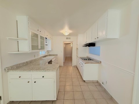 A kitchen with white cabinets and a granite countertop.