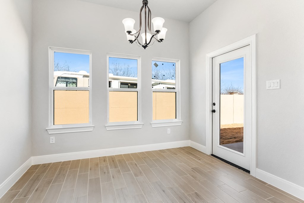 an empty room with windows and a door with a chandelier