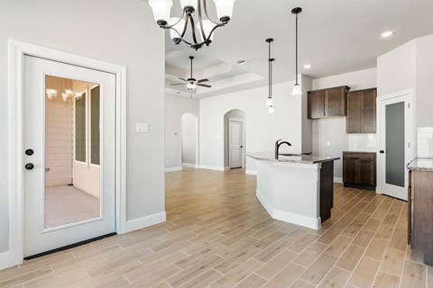 an open kitchen and living room with a door to a hallway