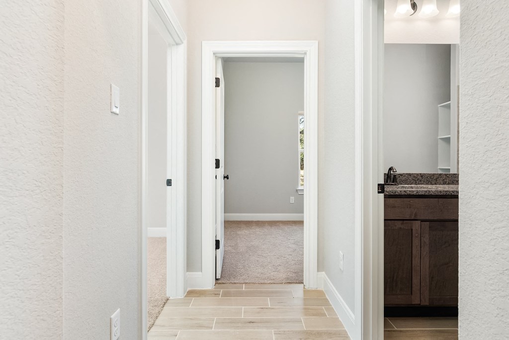 a hallway with an open door to a bathroom and a closet