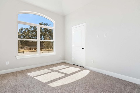 an empty bedroom with a window and a door