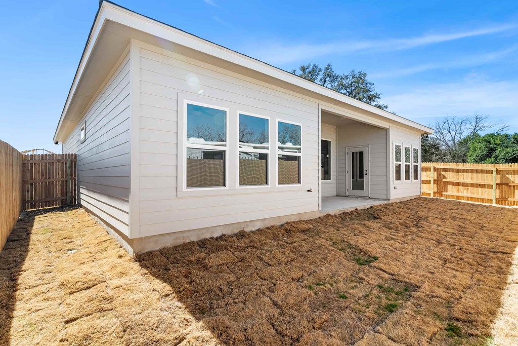 the front of a white house with a yard and a fence