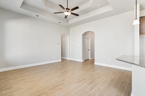 an empty living room with a ceiling fan and hardwood floors
