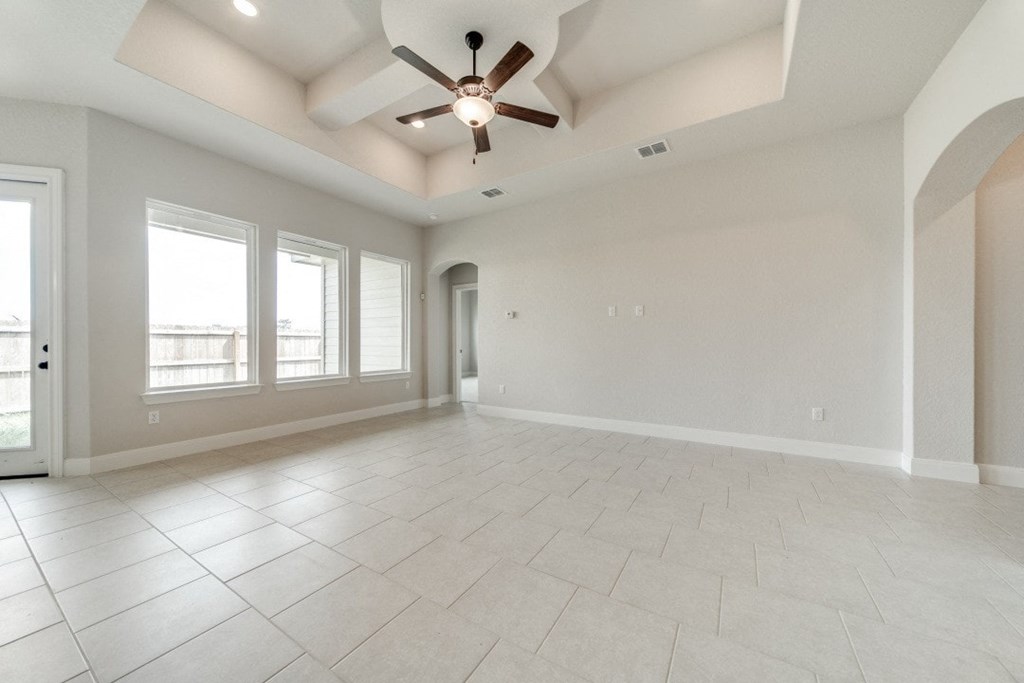 an empty living room with a ceiling fan and windows