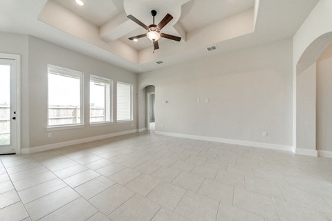 an empty living room with a ceiling fan and windows