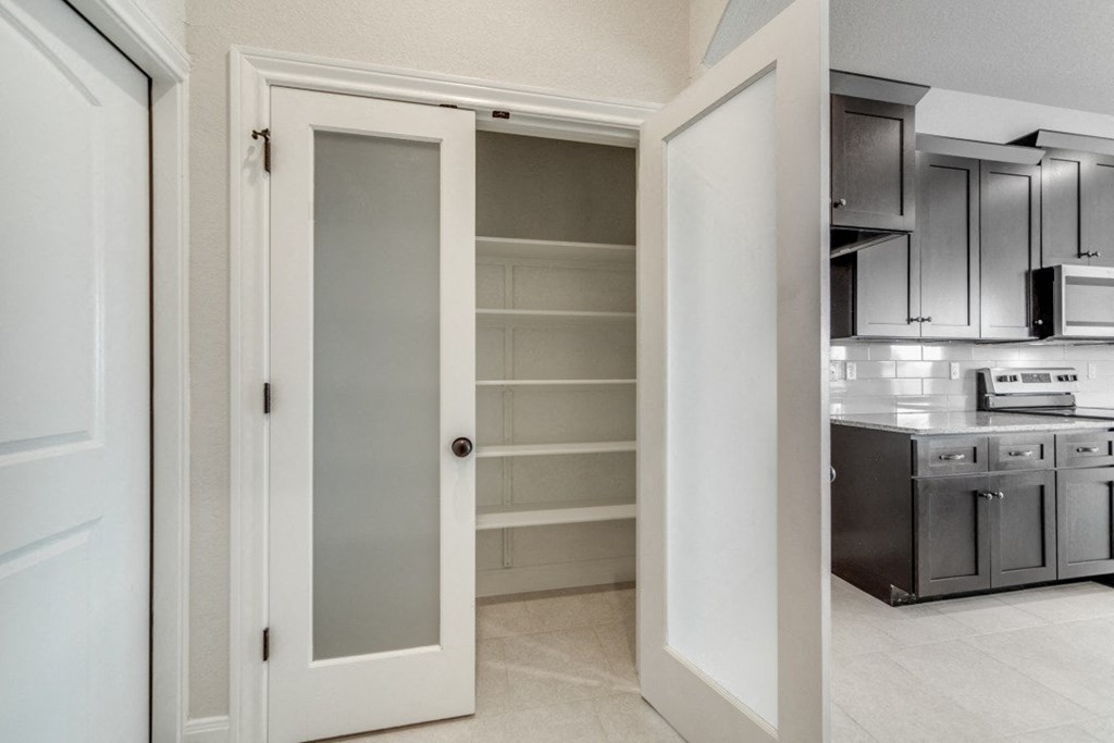 a kitchen with an open door to a pantry
