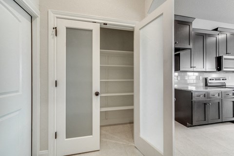 a kitchen with an open door to a pantry