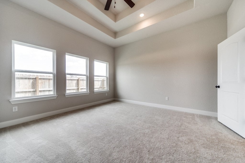 an empty living room with three windows and a ceiling fan